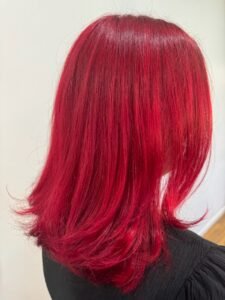 Vibrant red hair with a sleek and shiny finish, styled for a bold and confident look.